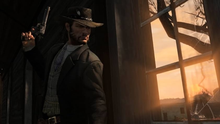 A man looks out a window at dusk. 