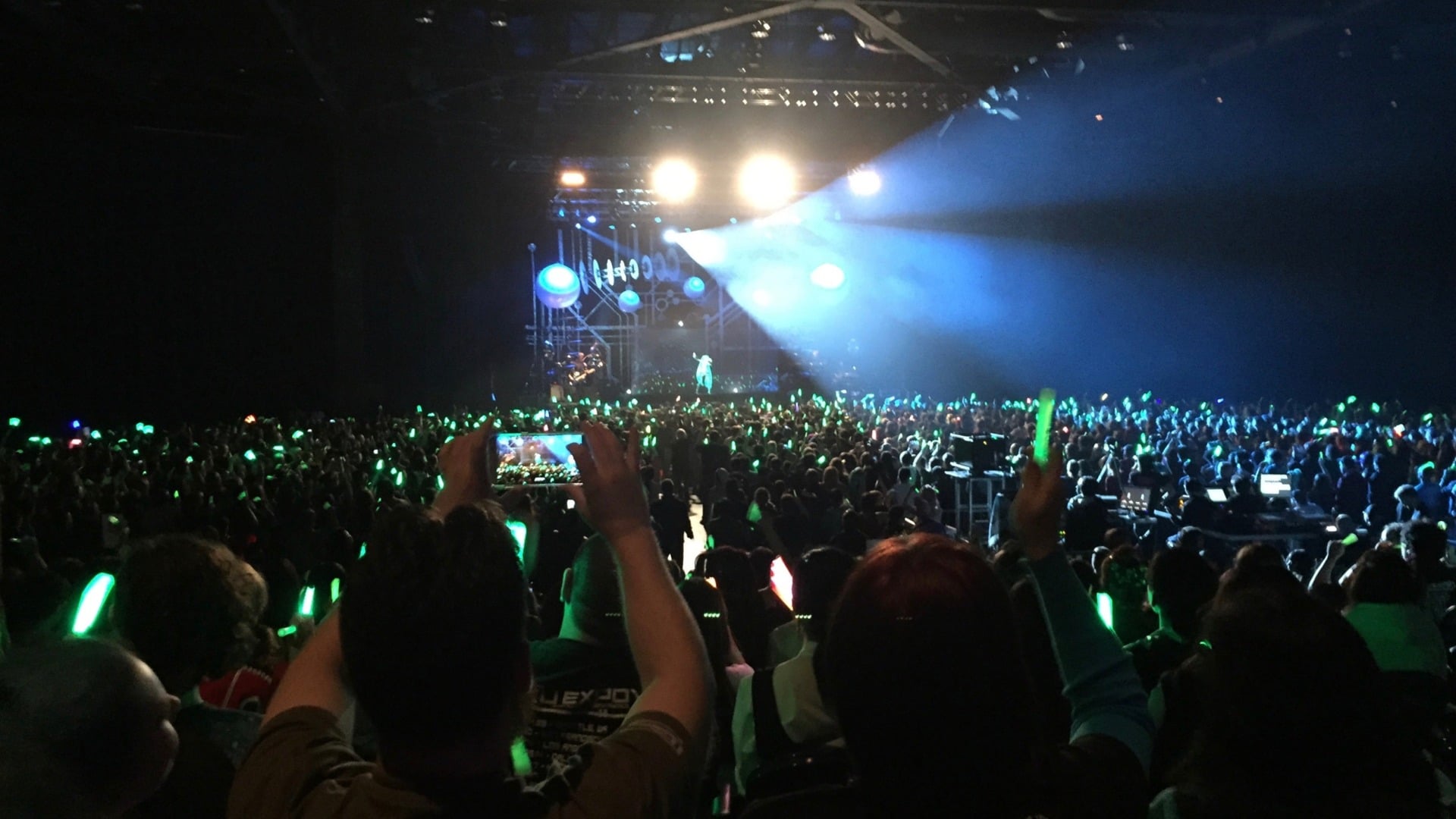 A guy with a phone recording a singer on a screen, captured by me with my phone, viewed by you on your own screen