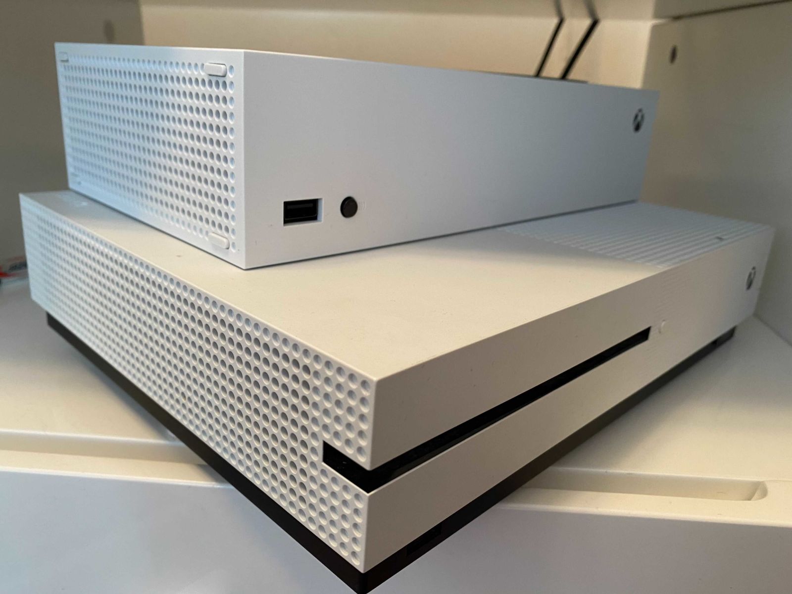 The Xbox Series X sitting atop the much larger Xbox One S. 