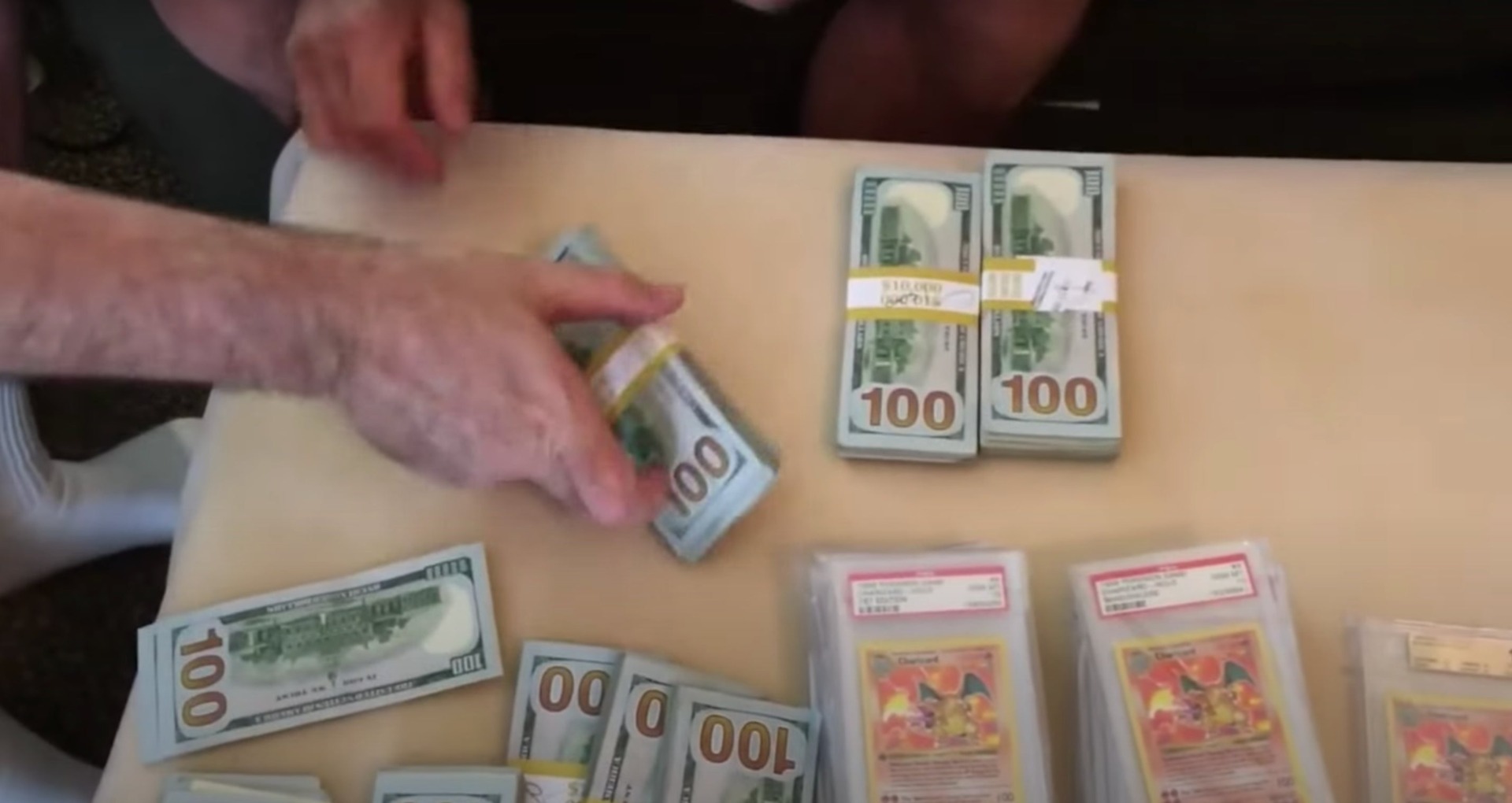 Gary Haase shows off a portion of money gained from selling stakes in the Charizard card collection. There are many more stacks of bills not pictured in the frame.