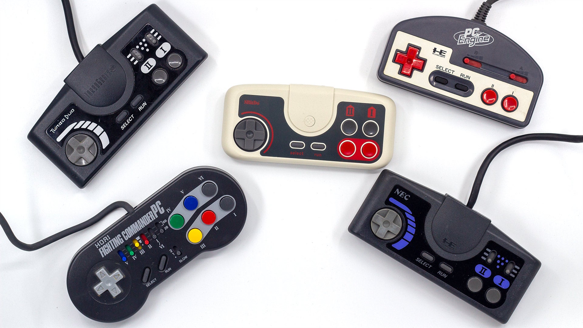 Four vintage PC Engine / TurboGrafx-16 controllers surround a 2.4GHz wireless 8BitDo PC Engine gamepad for some kind of hazing ritual.