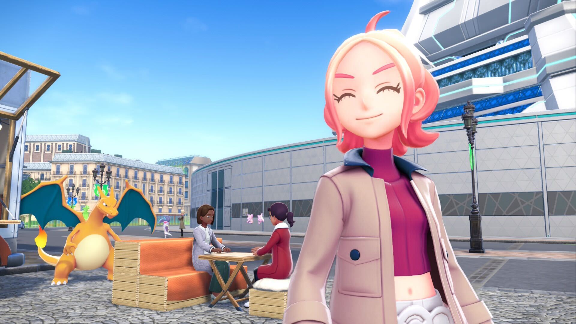 Taunie smiles at something off-screen with people eating at a table behind her next to a Charizard.