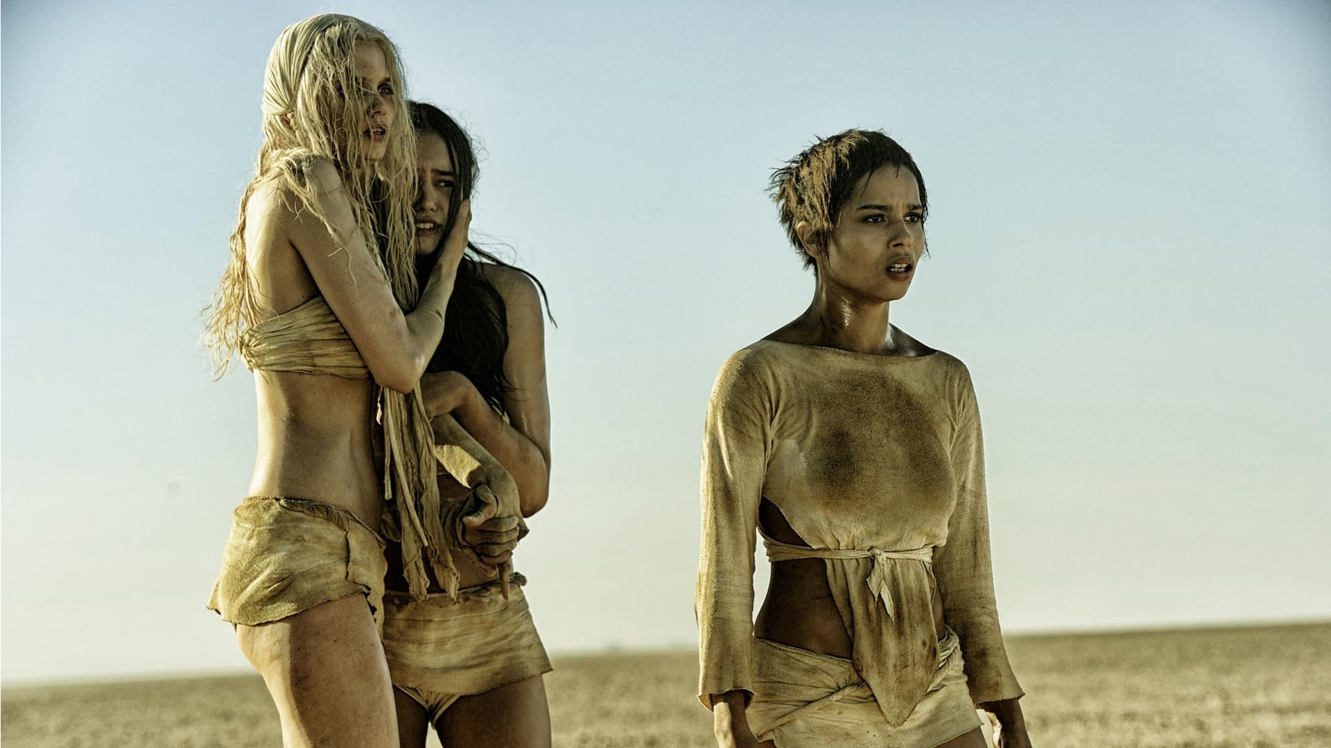 Scantly clad women in Mad Max: Fury Road stare out at something beyond the camera.