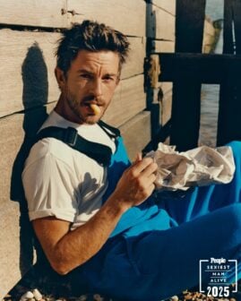 Jonathan Bailey for People's Sexiest Man Alive issue sits on the ground while eating.