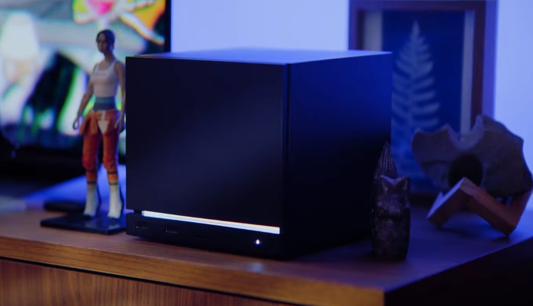 A Steam Machine sits on a desk with an action figure.
