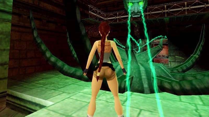 Lara stands in front of a green glowy something.