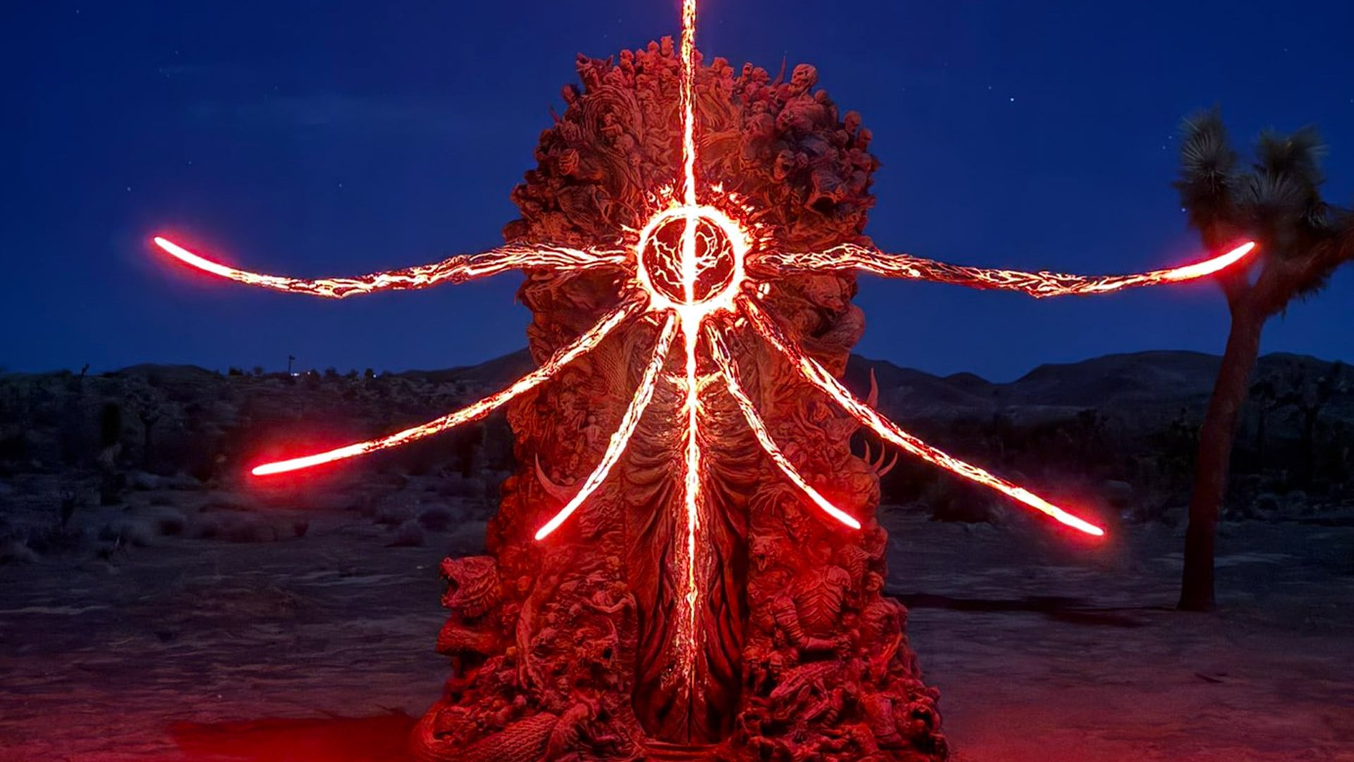 An ominous statue of skeletons stands glows in the desert at night.