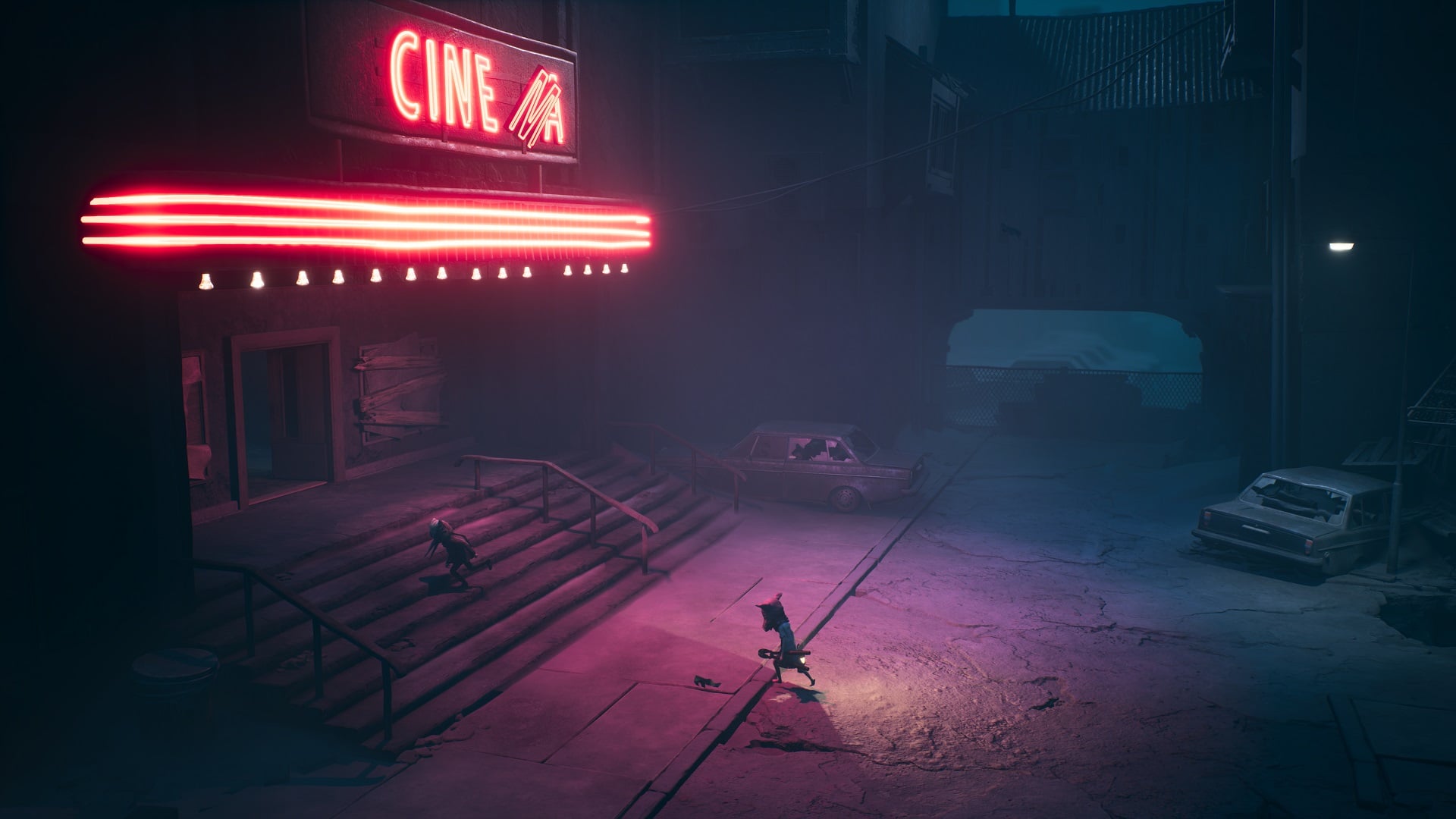 A neon sign appears overtop a movie theater. 