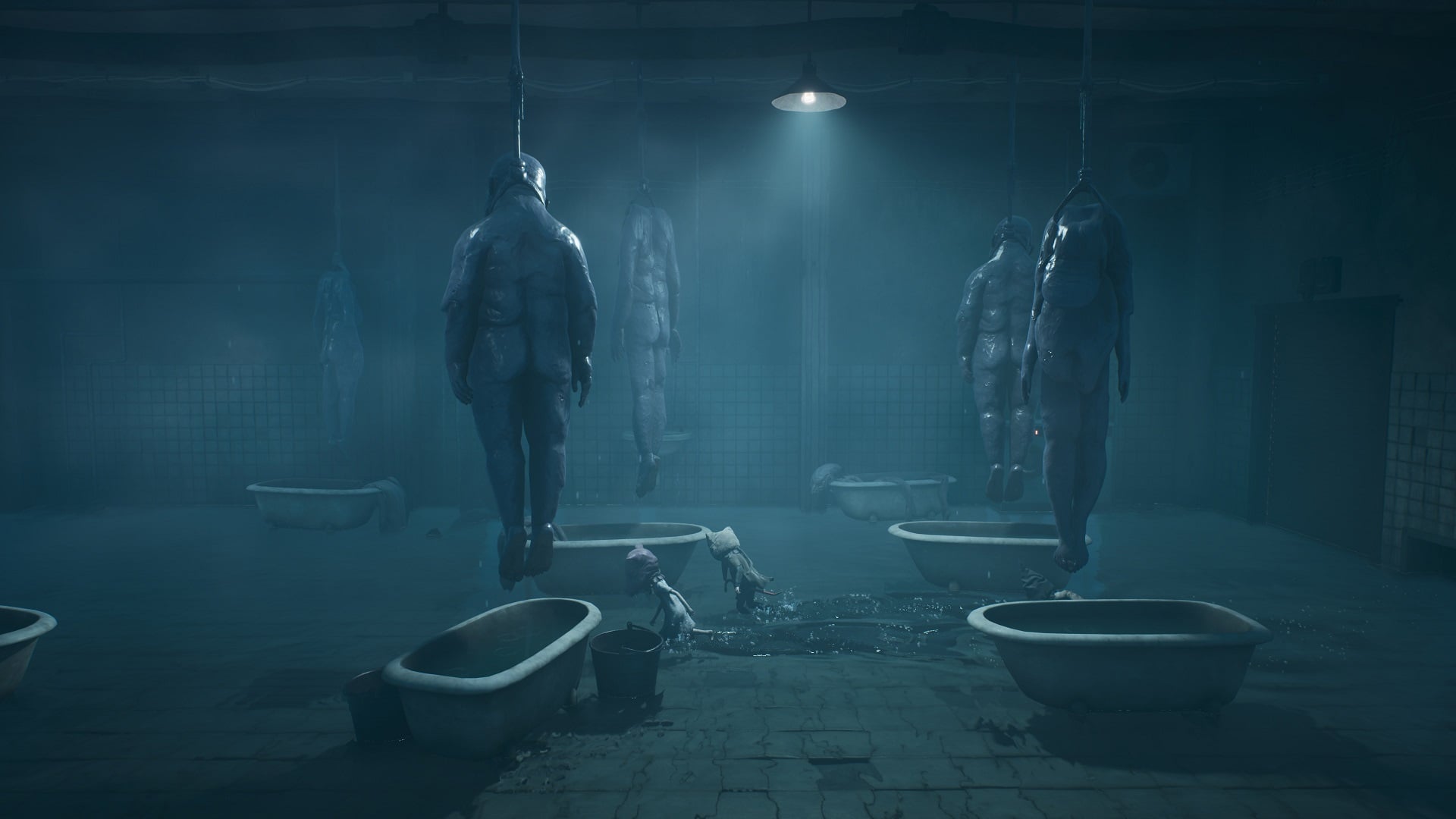 A laundry room is full of tubs with bodies hanging over them. 