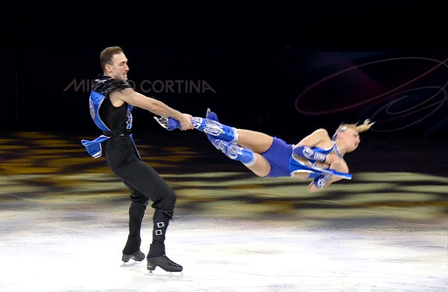 A man swings a woman on the ice.