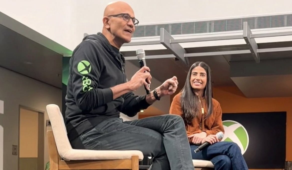 Satya Nadella sits with Asha Sharma in a meeting.